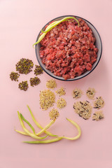 Natural raw ingredients for pet food on pink background. Flat lay.