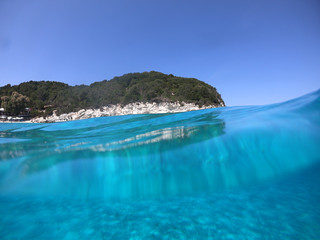 Underwater photo of tropical paradise turquoise exotic beach of Voutoumi with sail boats docked in island of Antipaxos, Ionian, Greece