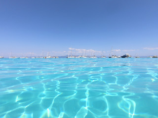 Underwater photo of tropical paradise turquoise exotic beach of Voutoumi with sail boats docked in island of Antipaxos, Ionian, Greece