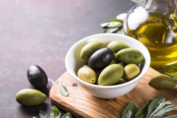 Olives and olive oil on dark stone table.