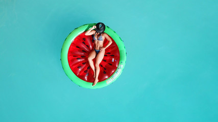 Aerial drone top photo of unidentified woman wearing a hat sitting in inflattalbe watermelon in...