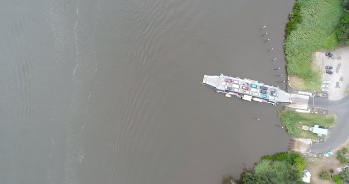 Cargo vehicle ferry on Hawkesbury river around Wiseman ferry town in NSW of Australia. Mighty river loops around town cape in aerial top down view.
