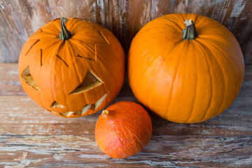 halloween, holidays and decoration concept - jack-o-lantern or carved pumpkin on wooden table at home