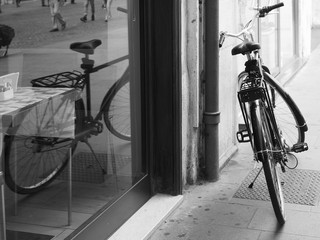 Fototapeta na wymiar A bicycle reflected in the window of a cafe. Black and white photo.