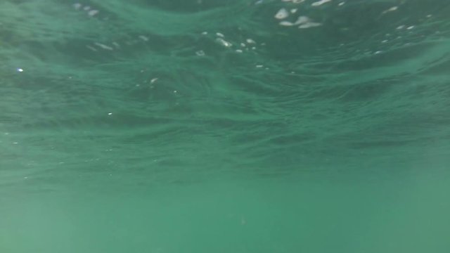 Rapid movement under blue water near a surface with waves