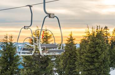 Fototapeta na wymiar ski lift with seats going over the snow mountain in ski resort.