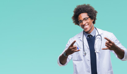 Afro american doctor man over isolated background shouting with crazy expression doing rock symbol with hands up. Music star. Heavy concept.