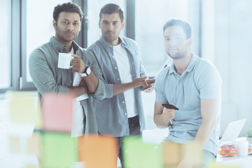 Obraz premium selective focus of young multiethnic businessmen looking at sticky notes while working at new project together