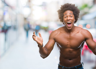 Fototapeta na wymiar Afro american shirtless man showing nude body over isolated background celebrating crazy and amazed for success with arms raised and open eyes screaming excited. Winner concept