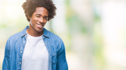 Afro american man over isolated background winking looking at the camera with sexy expression, cheerful and happy face.