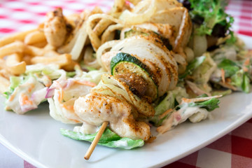 Delicious dish from Hungarian cuisine - chicken skewers with vegetables grilled on bbq and served with fresh coleslaw salad and french fries