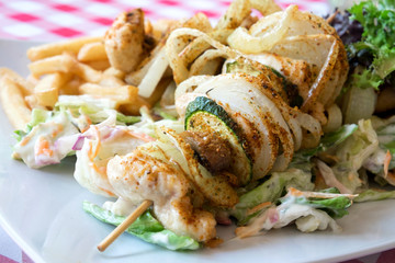 Delicious dish from Hungarian cuisine - chicken skewers with vegetables grilled on bbq and served with fresh coleslaw salad and french fries