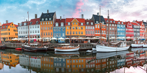Nyhavn at sunrise, with colorful facades of old houses and old ships in the Old Town of Copenhagen, capital of Denmark.