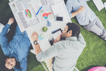 Young businessmen sleeping on the table and green grass carpet at modern office, business teamwork