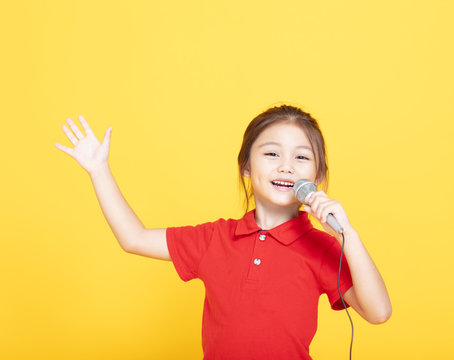 happy little girl singing on yellow background