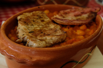 Delicious dish from traditional Balkan cuisine - beans stewed with tomato sauce and sweet chili (paprika) and served with grilled meat and ham