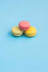 Top view of yellow, green and pink macarons or macaroons on turquoise background.