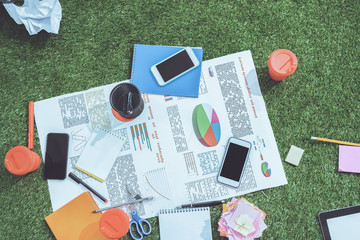 heap of business objects and office supplies laying on green grass carpet at office, business establishment