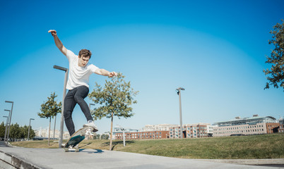 Fototapeta na wymiar Young attractive man riding and jumping longboard in the park.