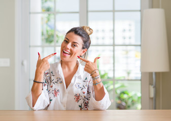 Young woman at home smiling confident showing and pointing with fingers teeth and mouth. Health concept.
