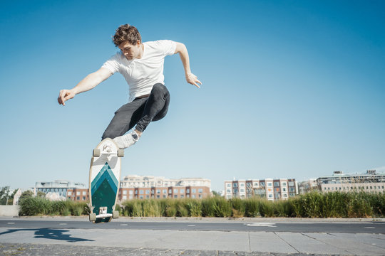 Young attractive man riding and jumping longboard in the park.