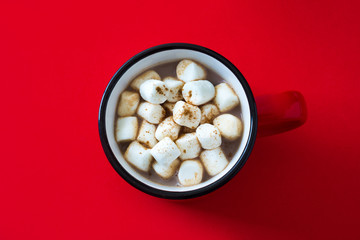 Christmas cocoa with marshmallow in mug on red background. Top view