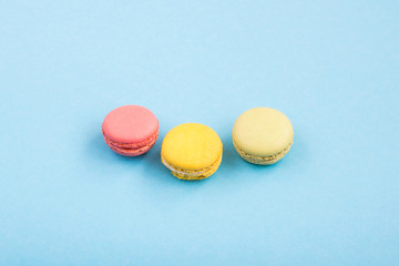 Colorful macaron, pink, yellow and green macaroons on blue background. Sweets, desserts. Copyplace, place for text.
