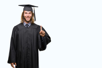 Young handsome graduated man with long hair over isolated background showing and pointing up with finger number one while smiling confident and happy.