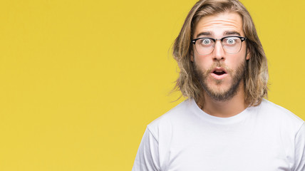 Young handsome man with long hair wearing glasses over isolated background afraid and shocked with surprise expression, fear and excited face.