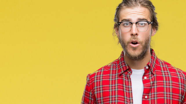 Young handsome man with long hair wearing glasses over isolated background afraid and shocked with surprise expression, fear and excited face.