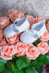 Bouquet of roses and pair of shoes for a newborn baby