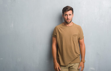 Handsome young man over grey grunge wall depressed and worry for distress, crying angry and afraid. Sad expression.