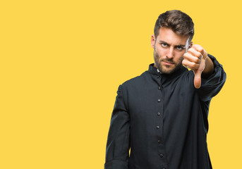 Young catholic christian priest man over isolated background looking unhappy and angry showing...