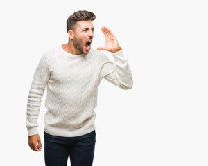 Young handsome man wearing winter sweater over isolated background shouting and screaming loud to side with hand on mouth. Communication concept.