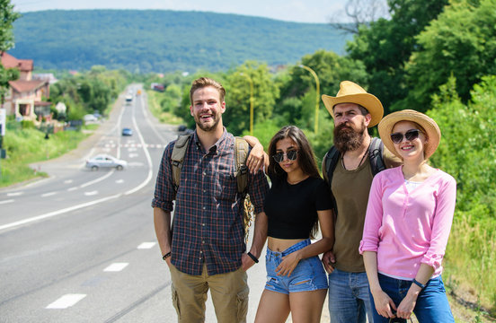 Company friends strats adventure with hitchhiking. Friends hitchhikers looking for transportation sunny day. Family weekend. Company friends travelers hitchhiking at edge road nature background