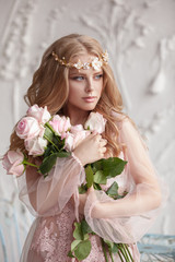 Delicate portrait of a young model girl. The image of the bride, a light lace dress in pink, a beautiful hairstyle and a natural make-up. Light photo studio, natural light from the window.