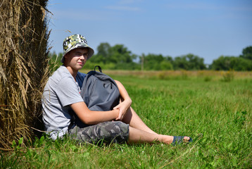 Naklejka na ściany i meble teenager with backpack sitting next to stack of straw