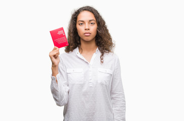 Young hispanic woman holding passport of Switzerland with a confident expression on smart face thinking serious