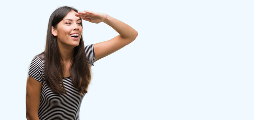 Young beautiful hispanic woman very happy and smiling looking far away with hand over head....