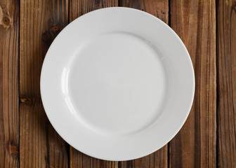 Empty white plate on wood. From above view.