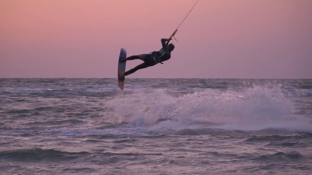 Slow-motion shooting, a male biker is riding the sea, splashing from kitesurf