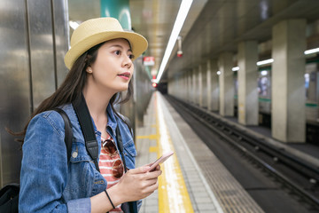 woman holding phone and waiting on platfom