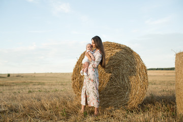 Naklejka na ściany i meble Mother and daughter in a field with stacks