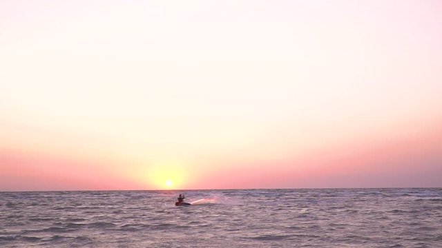 Performing a stunt on kitesurf against the dawn, kiter at dawn