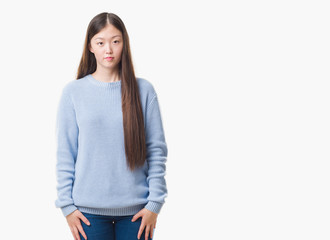 Young Chinese woman over isolated background with serious expression on face. Simple and natural looking at the camera.