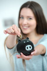 pretty young woman using a piggy bank
