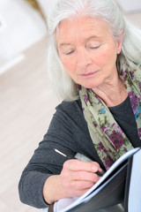 old woman writing notes at home