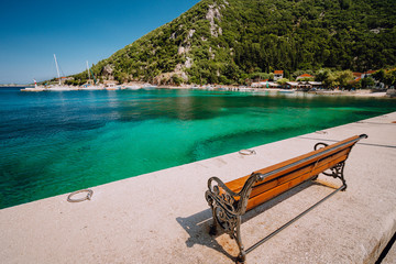 Wooden bench in front of the sea. Ecovillage at Ithaca island in Greece. Picturesque mediterranean town