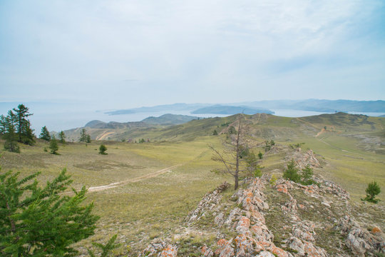 View at lake Baikal over a rocky steppe with larch trees.
