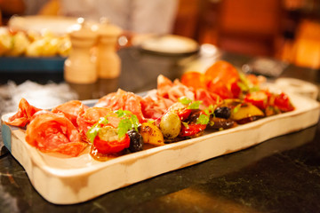 Assortment of tasty and delicious Italian antipasto. Prosciutto di Parma or Parma and Chorizo sausage with colorful grilled vegetable on a wooden board. Soft Focus. Warm Light.